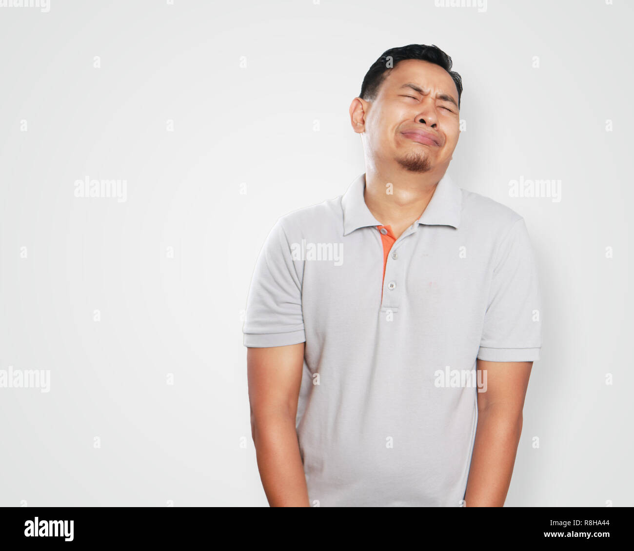 Photo image portrait of a cute handsome young Asian man crying hard, painful in his sensitive area gesture Stock Photo