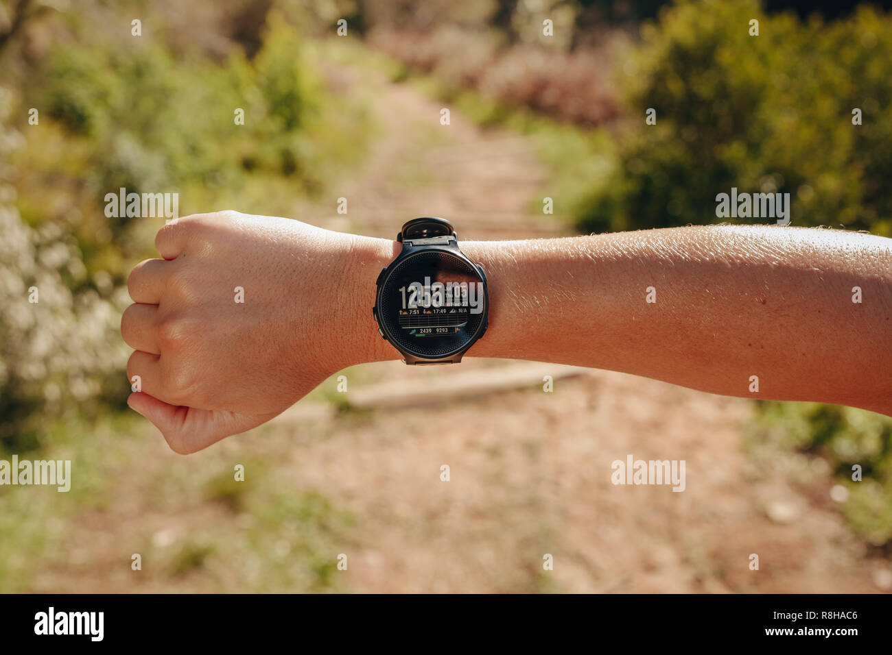 Person wearing a digital smart watch with many fitness tracking features. Smart watch in the hand of a fitness person on a sunny day. Stock Photo