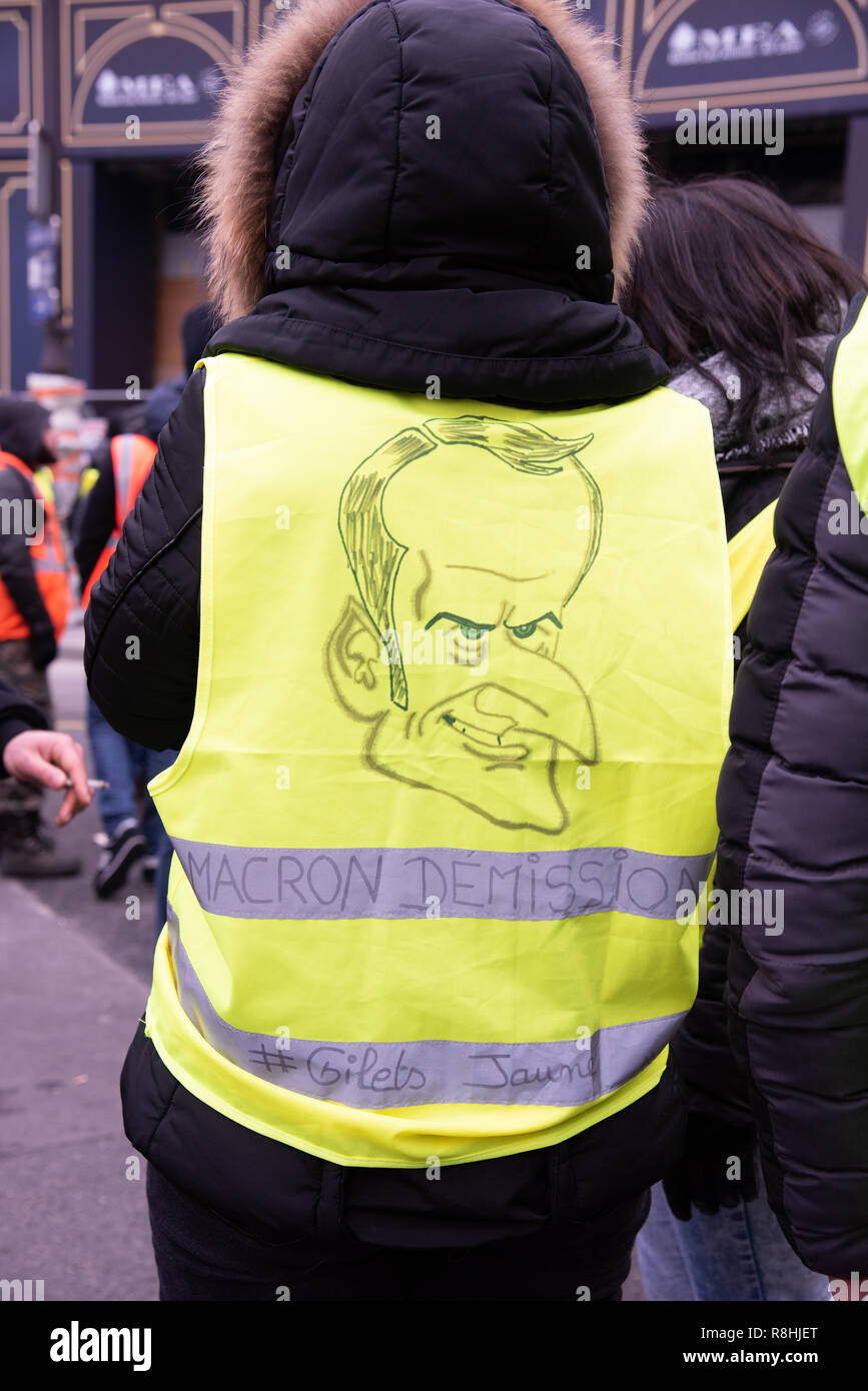 Paris, France, 15th December, 2018. Standing man wearing a yellow vest with  a caricature of French President Emmanuel Macron and asking for his  resignation. Around 2,000 protesters wearing yellow vests ("Gilets Jaunes")