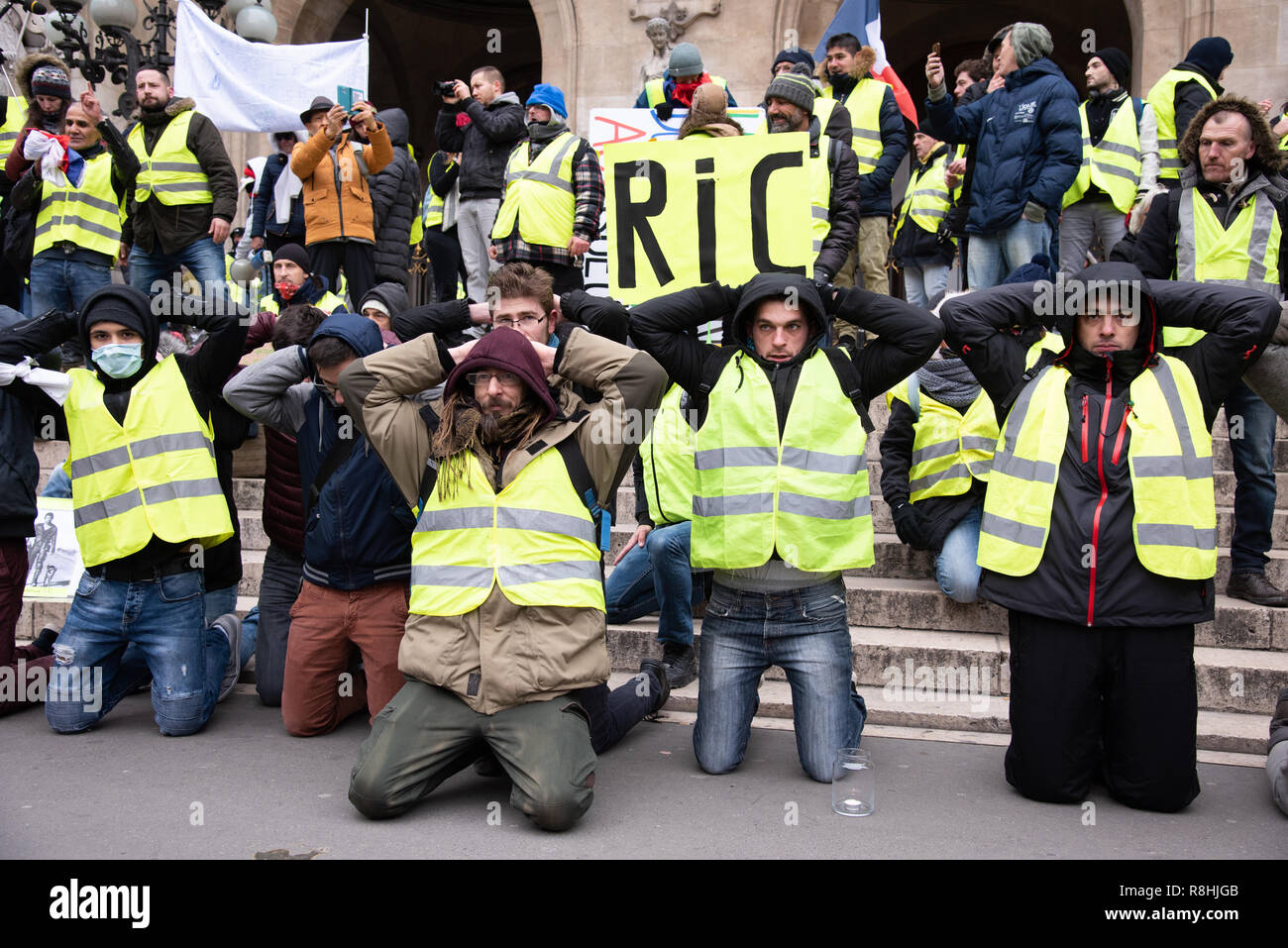 Paris, France, 15th December, 2018. Protesters kneeling, the hands above  their heads, in front of Garnier Opera House, Place de l'Opéra. Their  position reminds that of high school students who were arrested