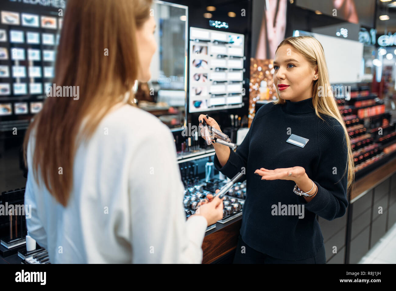 Seller consultant shows to female client eyeshadows in the make-up shop.  Cosmetics choosing in beauty store, makeup store Stock Photo - Alamy