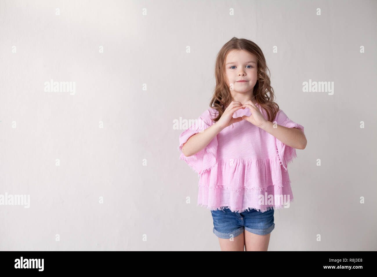 little girl in a pink dress shows hands heart Stock Photo - Alamy