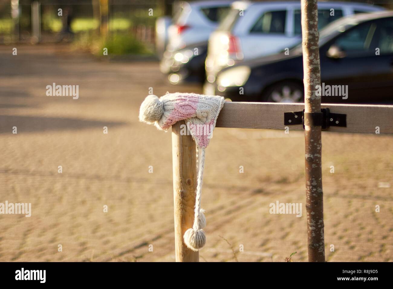 A pink and white woollen children's hat abandoned or lost in a car park Stock Photo