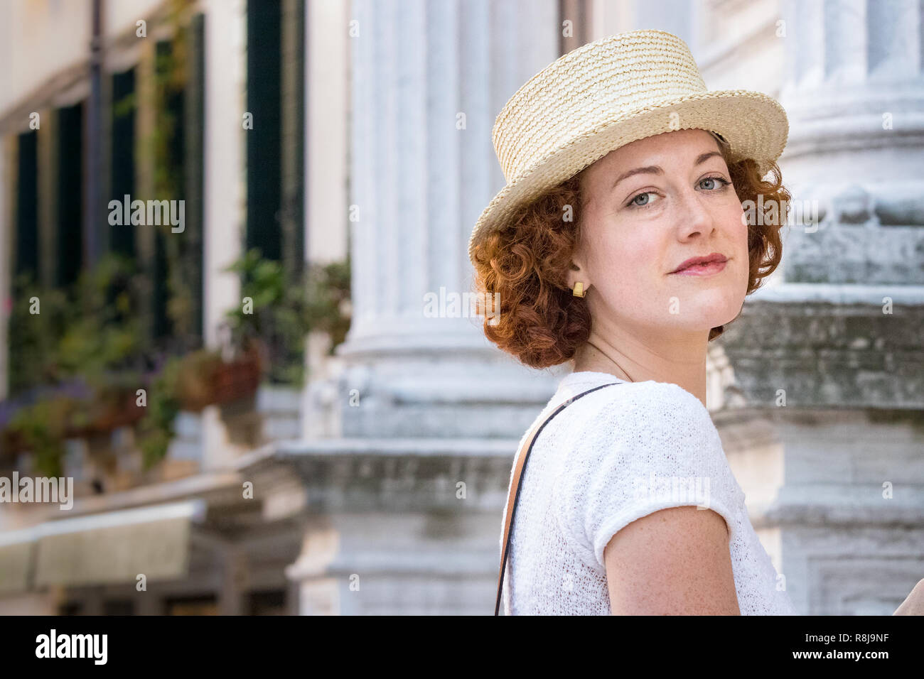 Venice, Italy - September 24th, 2018: Beautiful redhead lady wearing a straw panama hat walking in Venice, Italy. Stock Photo