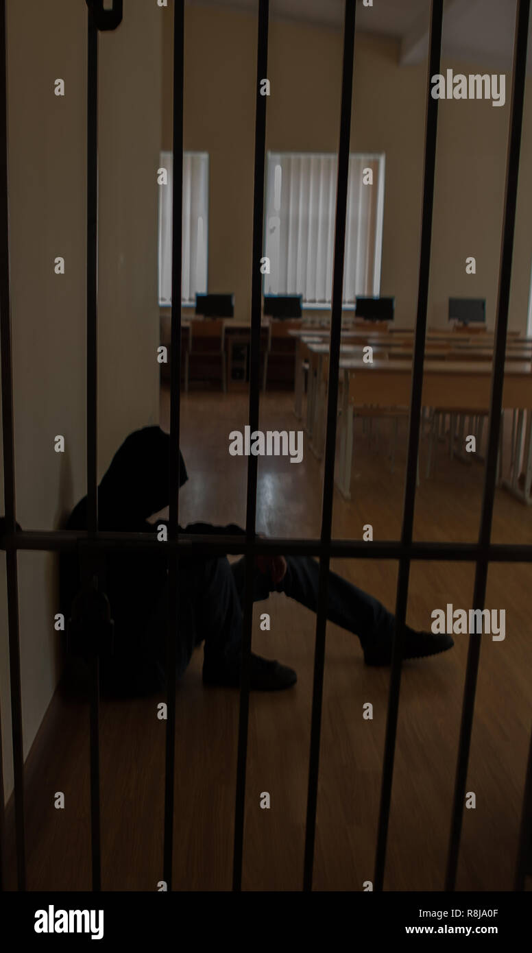 The prisoner behind the bars.Hold with hands on the grids in desperation Stock Photo