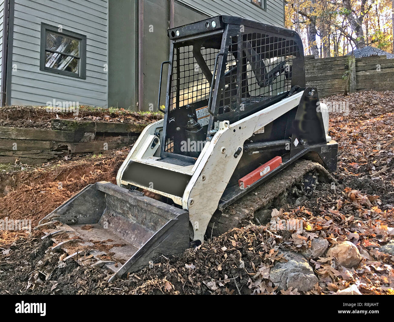 A small Bulldozer on the side of a house ready to get to work. Stock Photo