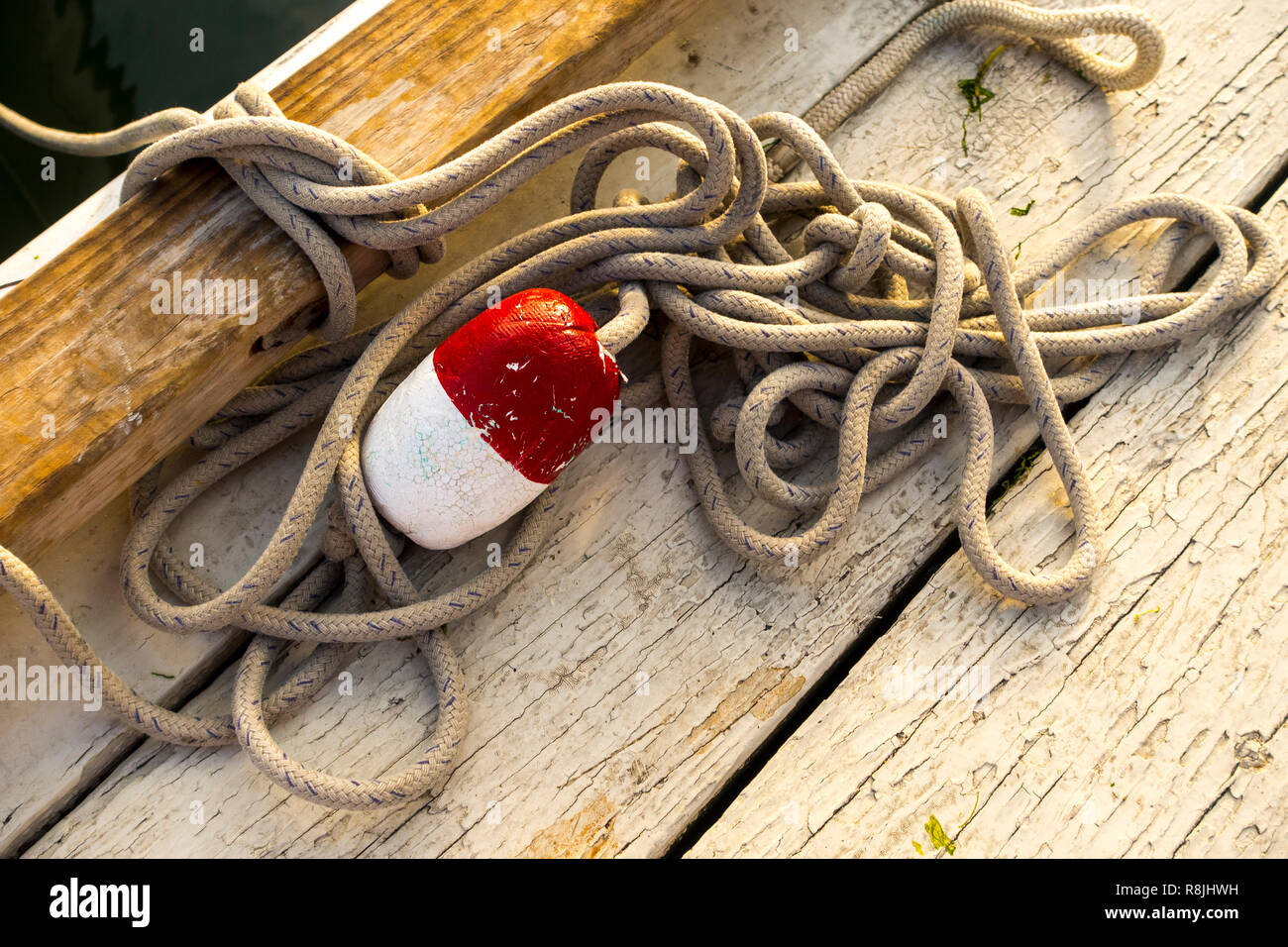 old fishing rope with floating red white buoy on a wooden dec or