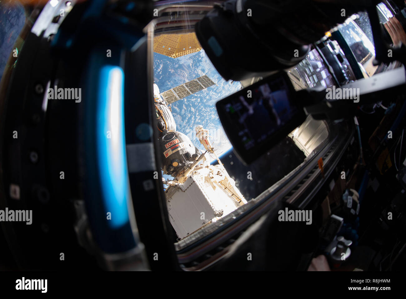View looking out from the International Space Station as Russian spacewalker Oleg Kononenko attached to the Strela boom inspect the Soyuz MS-09 spacecraft December 11, 2018 in Earth Orbit. During the spacewalk, he and fellow spacewalker Sergey Prokopyev, examined the external hull of the Soyuz crew ship docked to the Rassvet module. The area corresponded with the location of a small hole inside the Soyuz habitation module that was found in August and caused a decrease in the space station’s pressure. The hole was fixed internally with a sealant within hours of its detection. During the spacewa Stock Photo