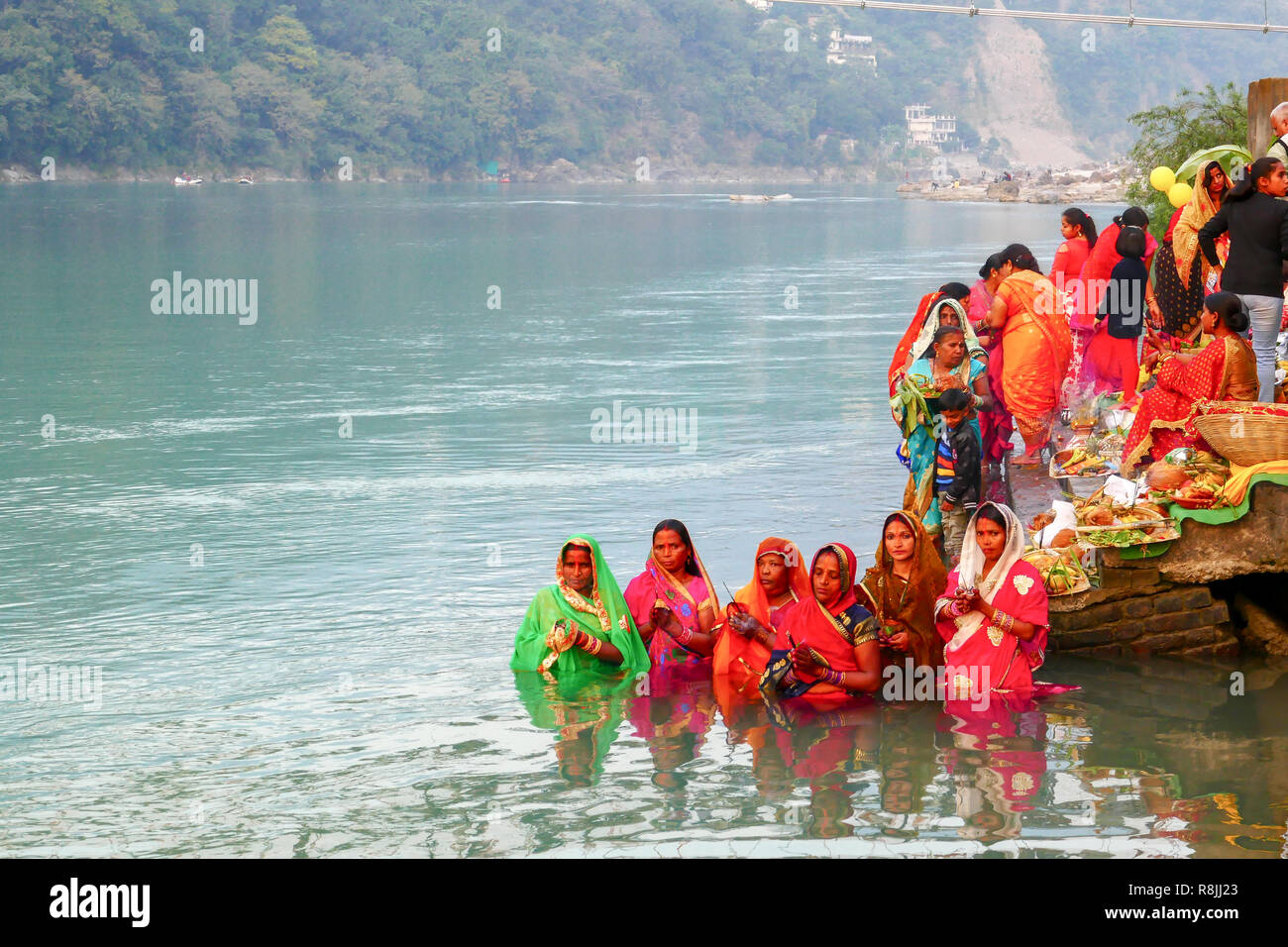 group of women in colourful saris praying in the water of river Ganga at Rishikesh, India Stock Photo
