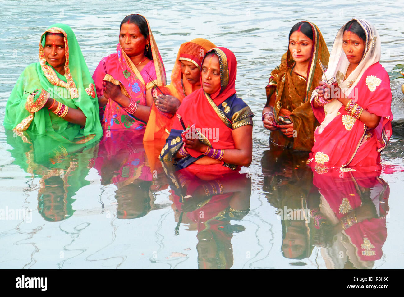 group of women in colourful saris praying in the water of river Ganga at Rishikesh, India Stock Photo