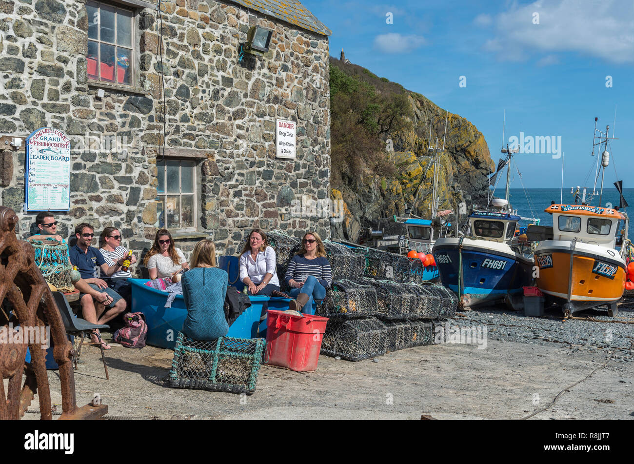 Having a drink in the summer sun at Cadgwith cove fishing village South coast Cornwall UK Stock Photo