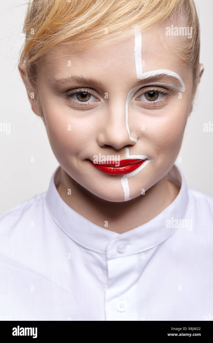 Portrait of a young smiling woman on gray background. Female with an unusual creative makeup and face painting. Stock Photo
