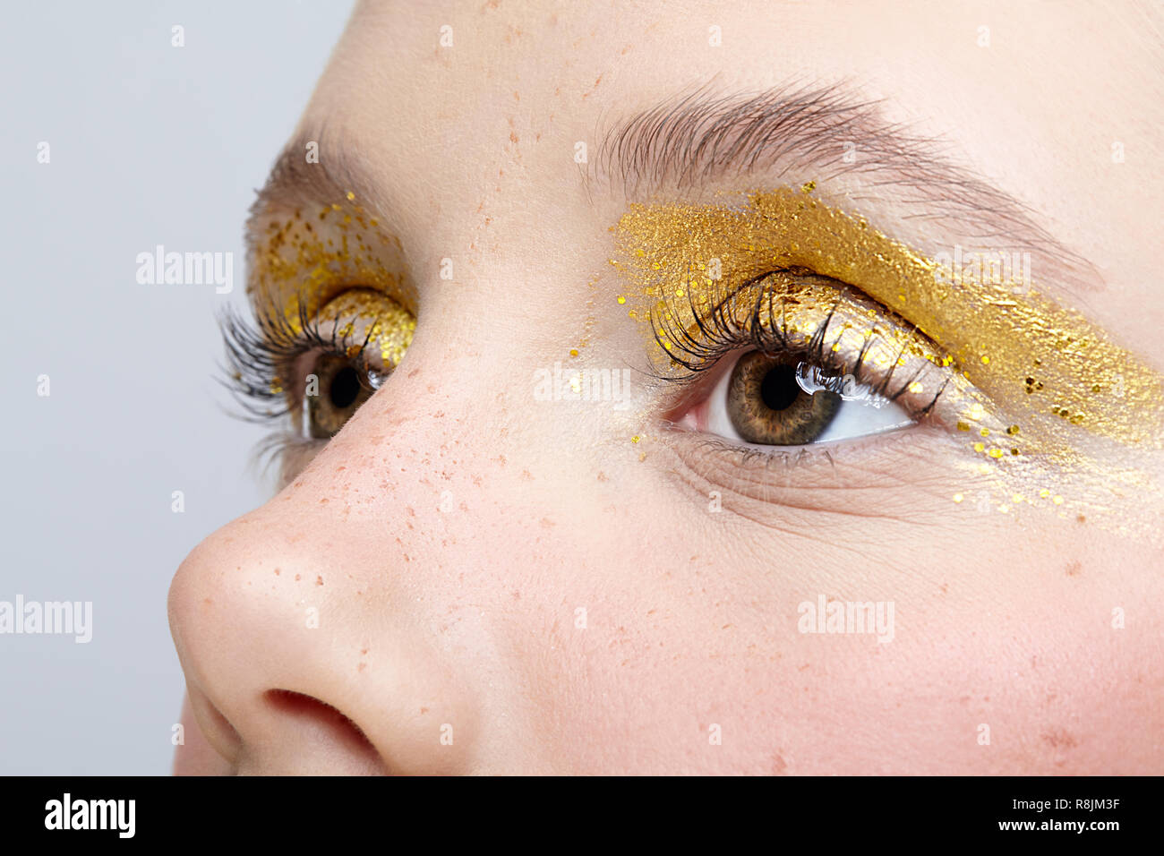 Closeup macro shot of  human female eye. Woman with unusual glitter glitzy vogue face beauty makeup. Girl with perfect skin and yellow smoky eyes eye  Stock Photo