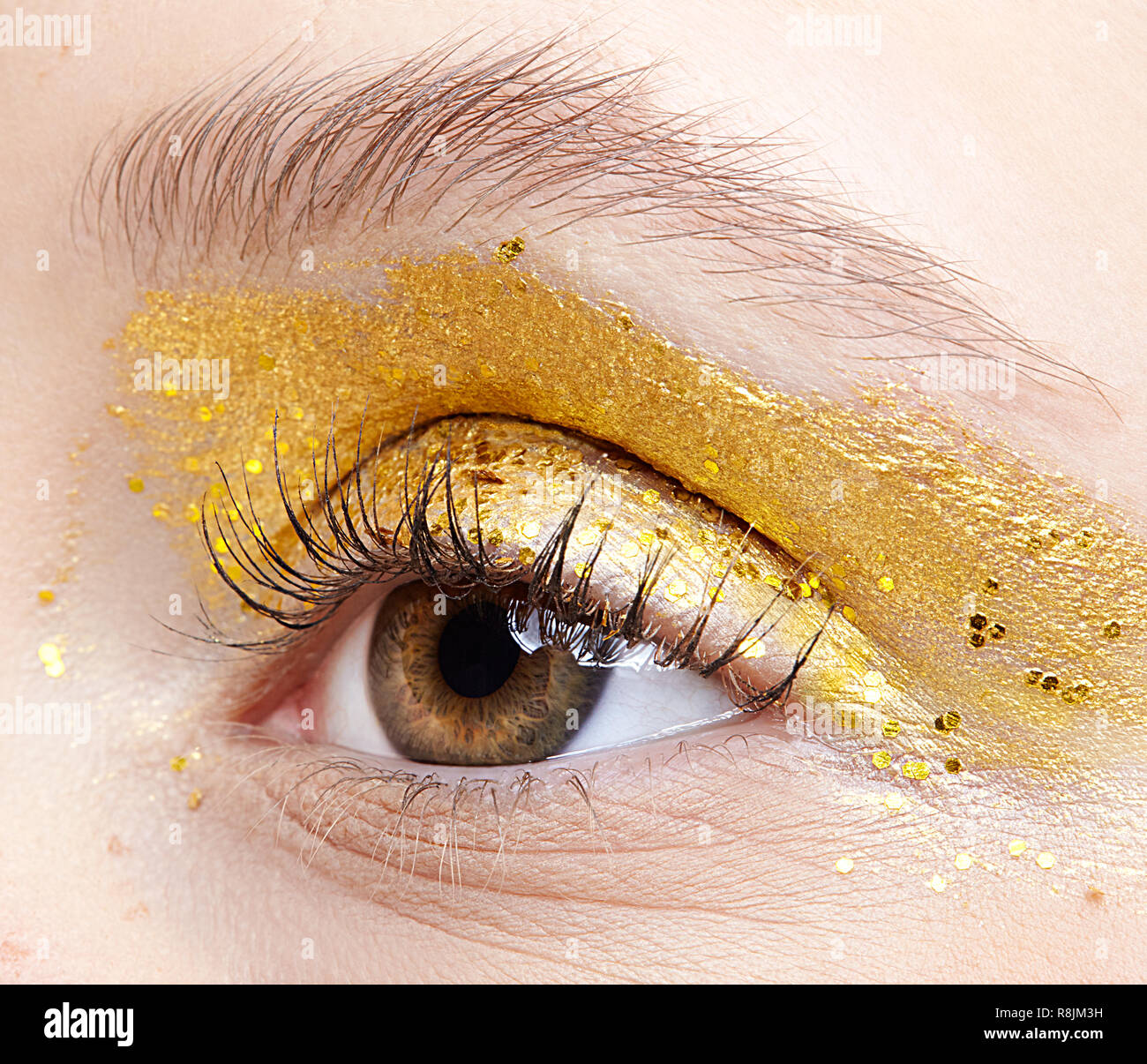 Closeup macro shot of  human female eye. Woman with unusual glitter glitzy vogue face beauty makeup. Girl with perfect skin and yellow smoky eyes eye  Stock Photo