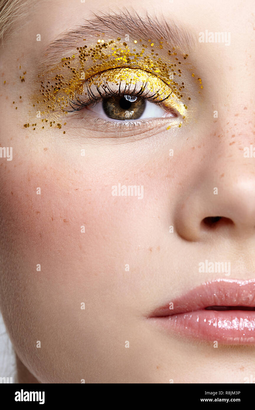 Closeup macro shot of  human female face. Woman with unusual glitter glitzy vogue face beauty makeup. Girl with perfect skin and yellow smoky eyes eye Stock Photo