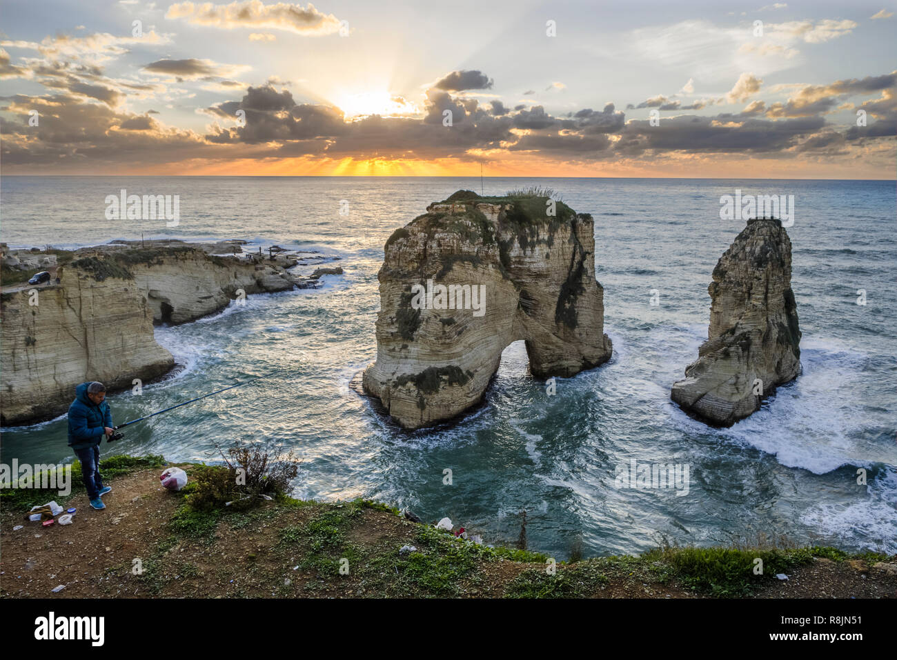 Fisherman next to Pigeon rock at sunset, Rawche, Beirut, Lebanon Stock Photo