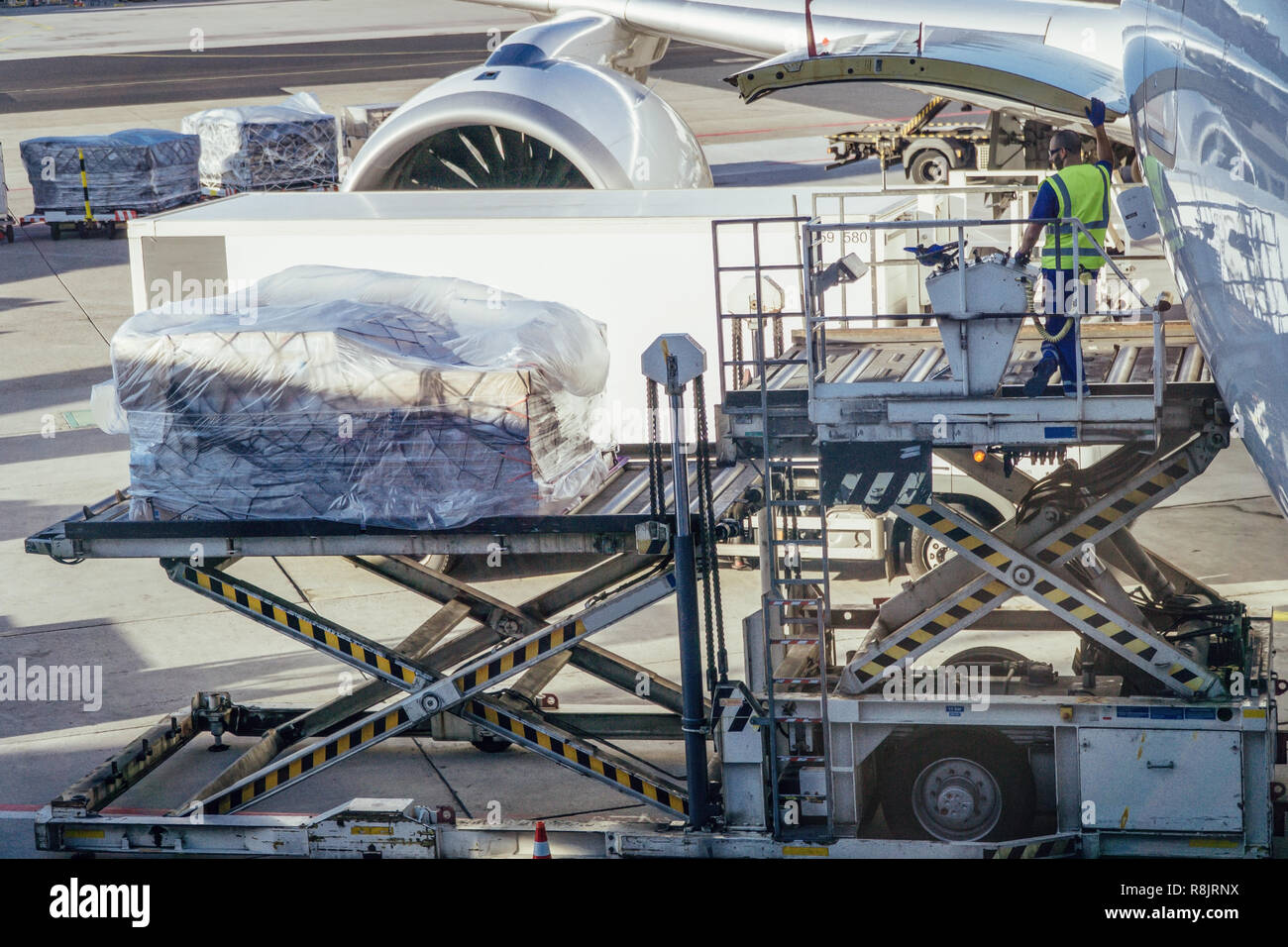 Airport employee handling cargo with a high loader for loading an airplane. Stock Photo