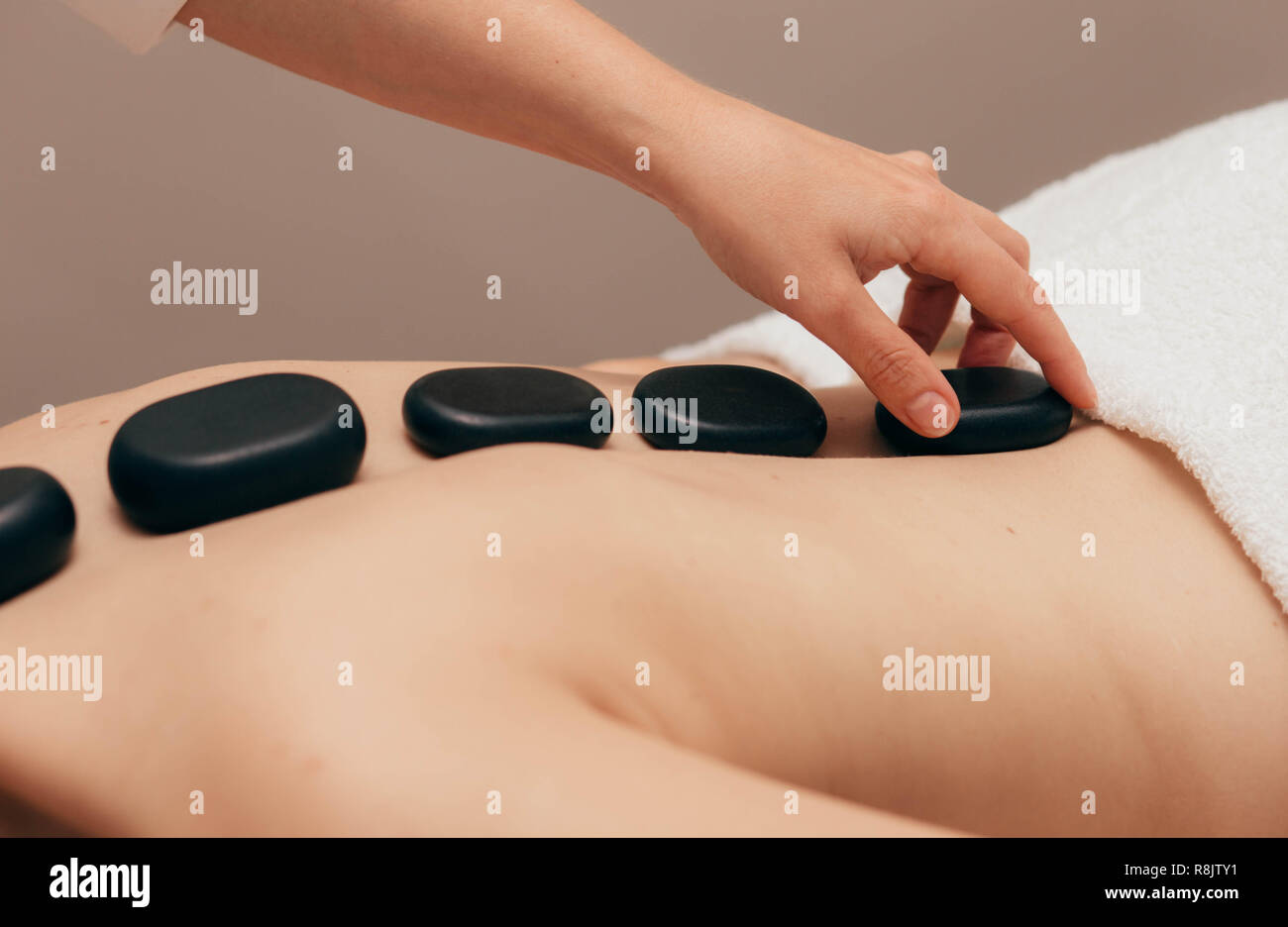 woman receiving hot stones treatment at spa salon. Hot stone massage treatment on human back Stock Photo