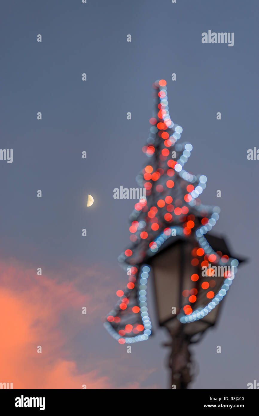 VILNIUS, LITHUANIA - DECEMBER 26, 2017:  The moon and illuminated Christmas decoration on a lantern during sunset at the Town Hall Square, Baltic Stock Photo