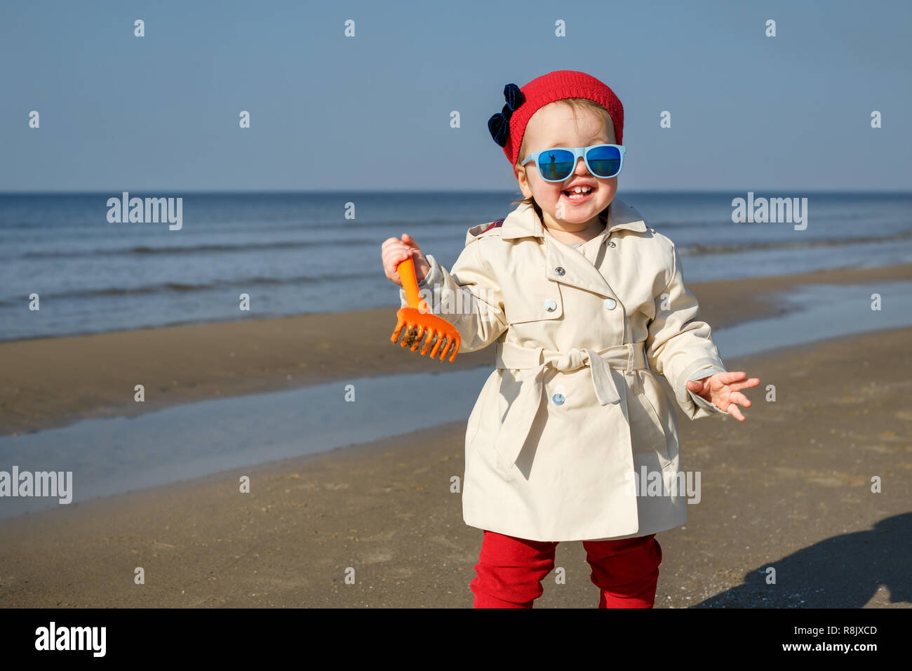 Happy little girl running on Baltic Sea beach in Latvia. Kids play in ocean sand dunes on cold autumn or spring day Stock Photo
