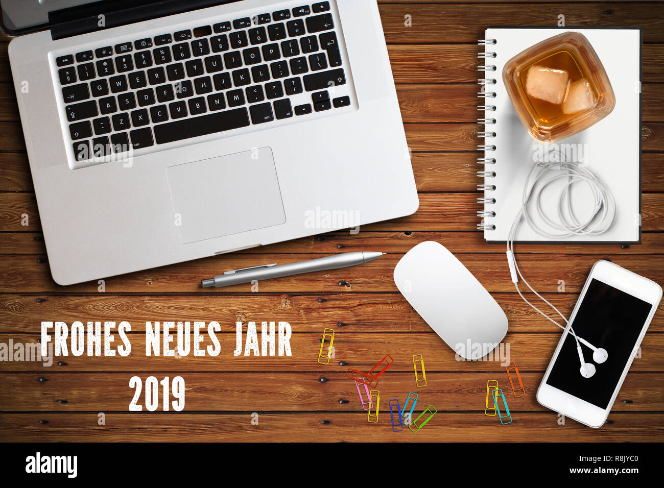 computer workspace with smartphone, a drink and the message "Happy new year 2019" in German on wooden background Stock Photo