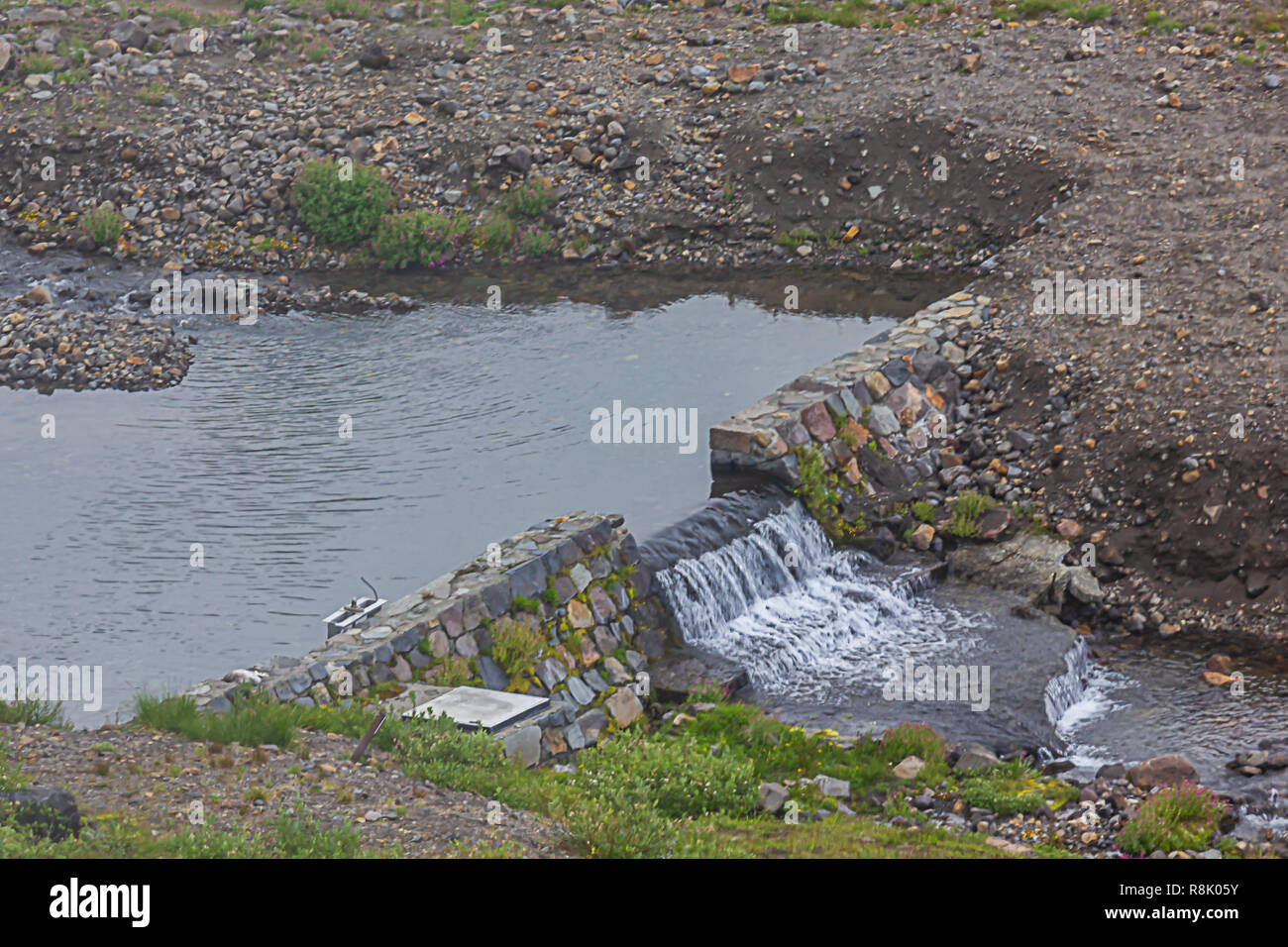 small pond lets water fall from dam at mount rainier Stock Photo