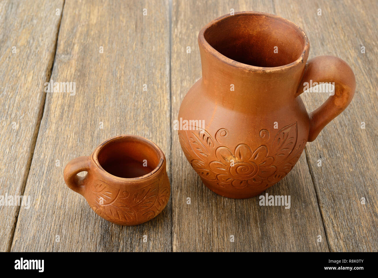 crock and a cup on a wooden surface Stock Photo
