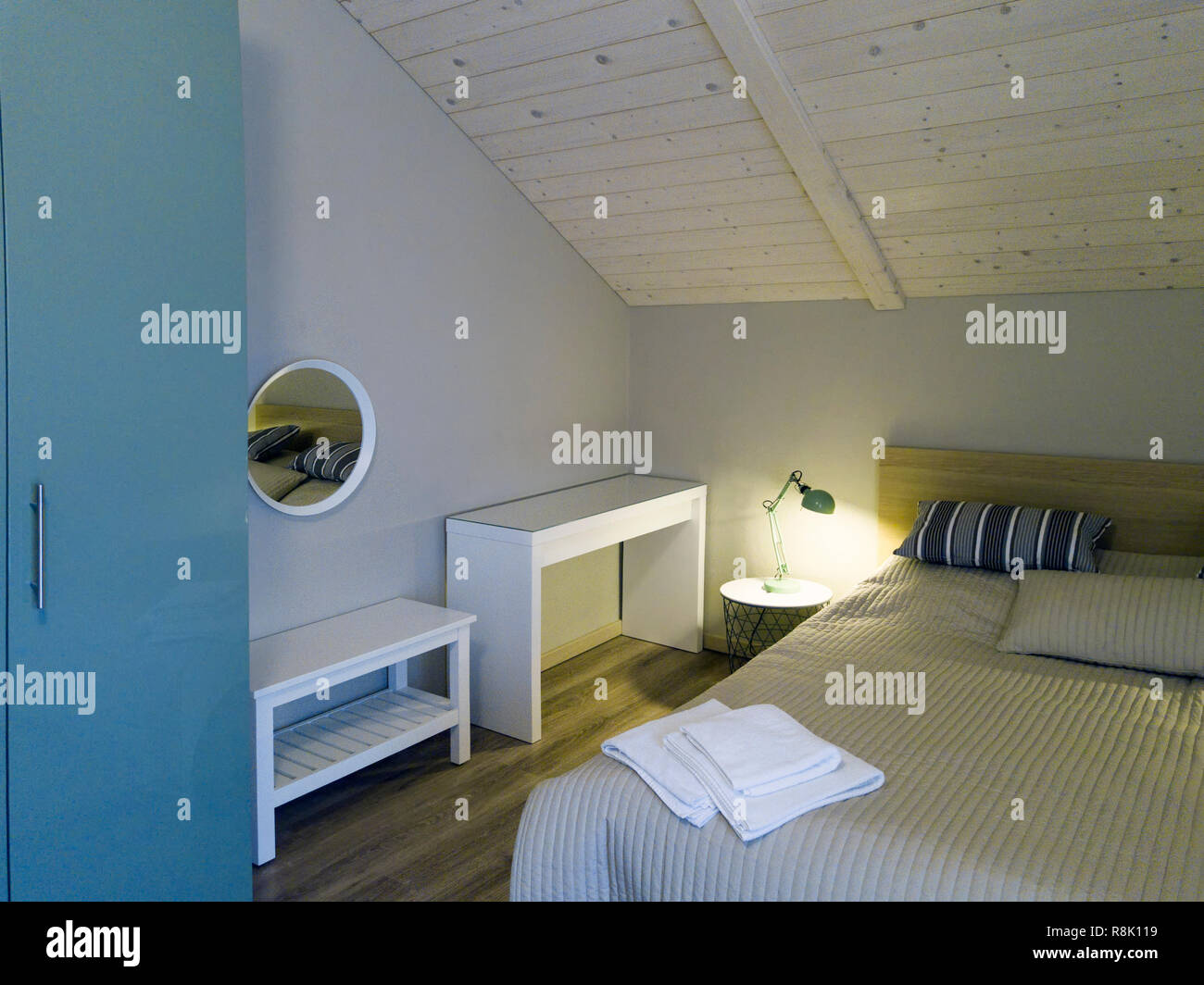 A bed with towels on a the blanket in a bedroom with wooden ceiling