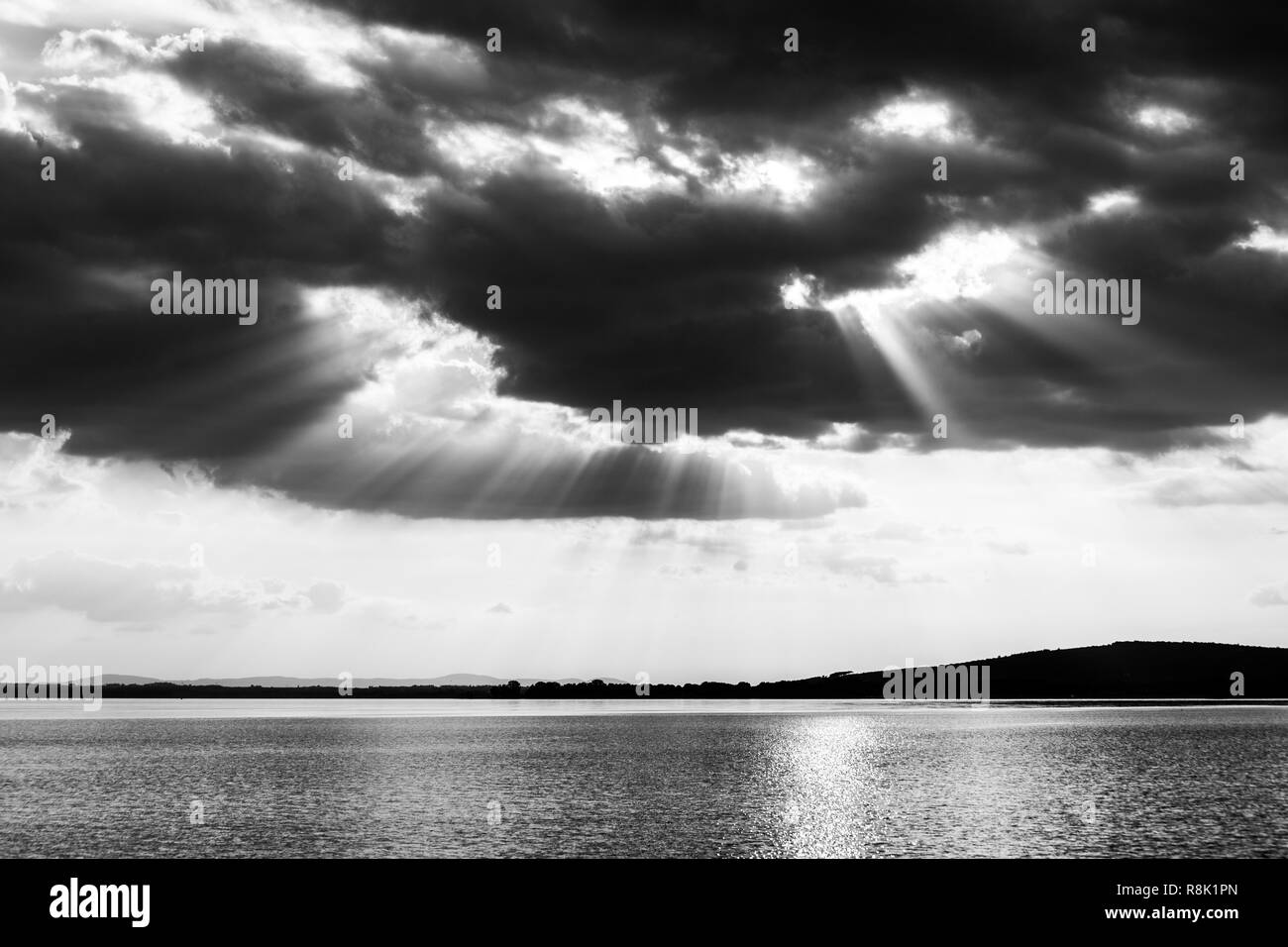 Beautiful sunset on a lake, with sunrays coming down under an overcast sky Stock Photo