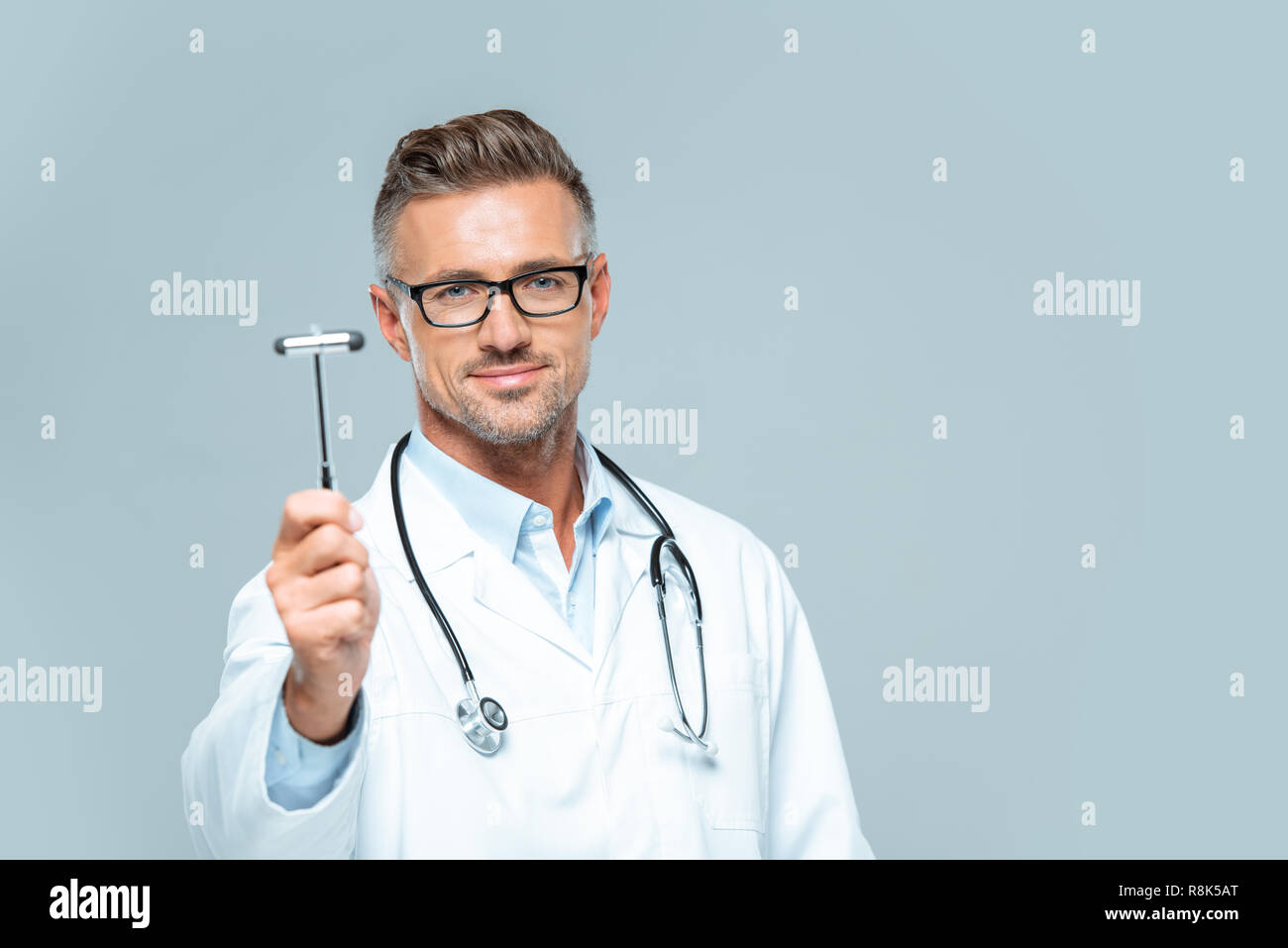 handsome neurologist with stethoscope on shoulders showing reflex hammer isolated on white Stock Photo