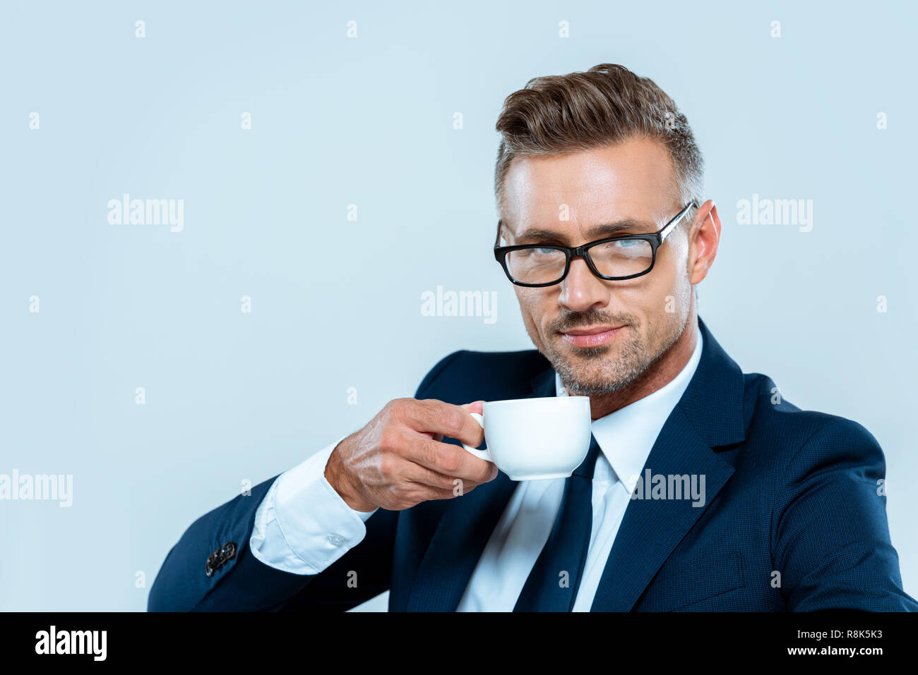 handsome businessman drinking coffee and looking at camera isolated on ...