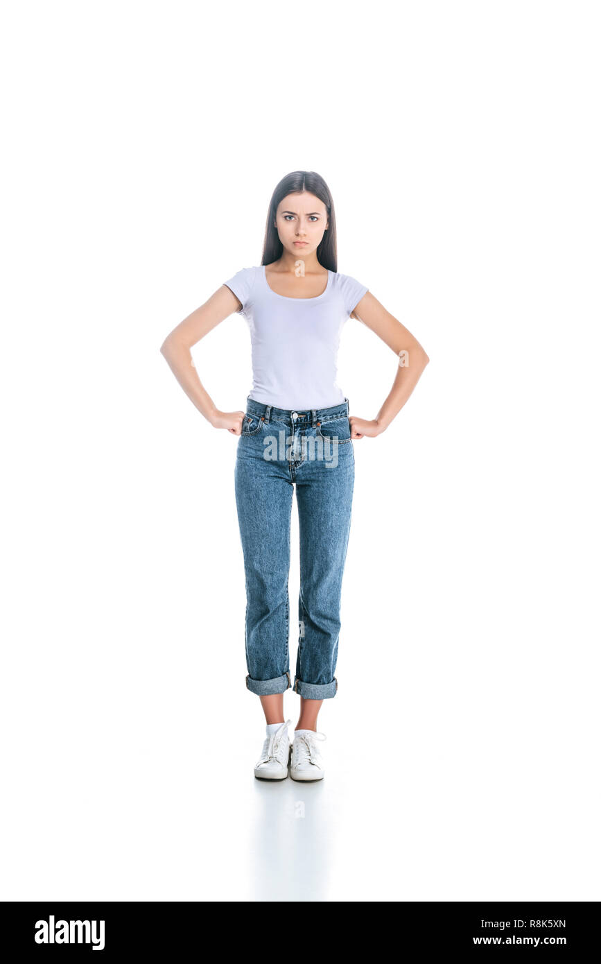 serious woman in stylish clothing standing akimbo isolated on white