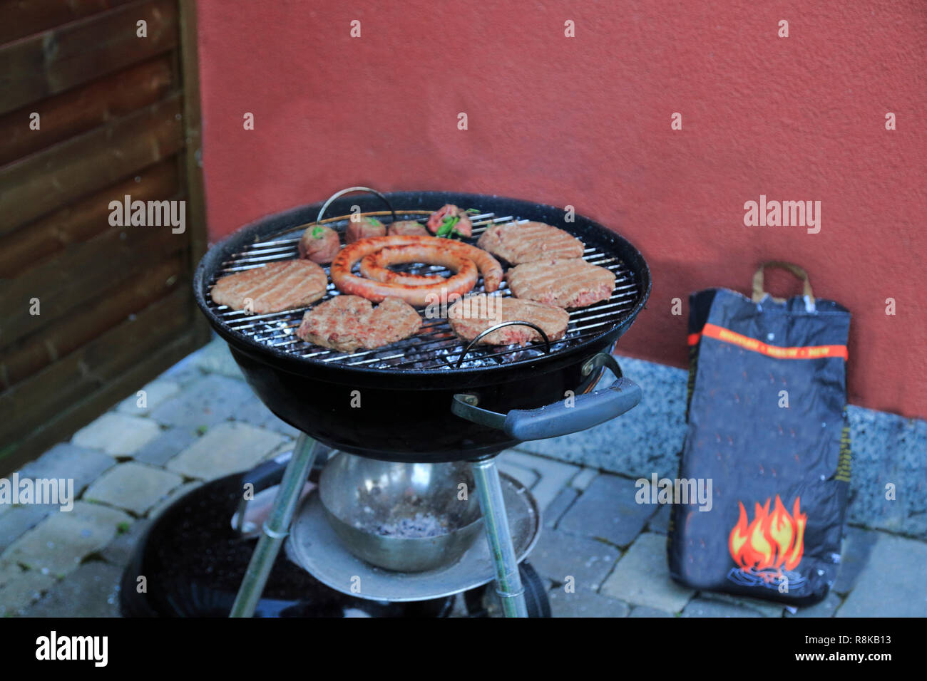 Paddies, Burger, Wurst und Fleischröllchen auf dem Holzkohle Grill Stock Photo