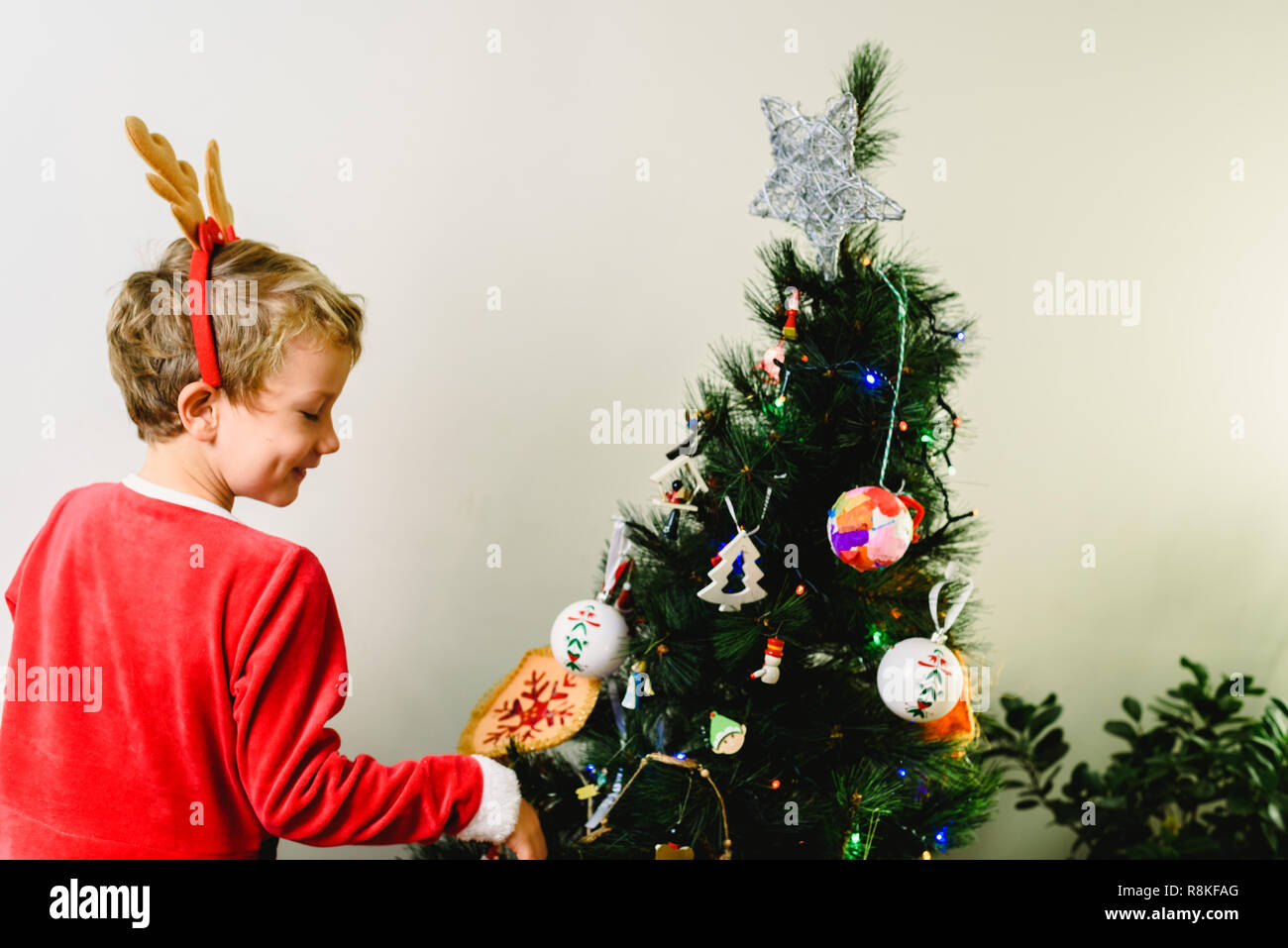 Child in Santa Claus costume, preparing the Christmas tree, back to
