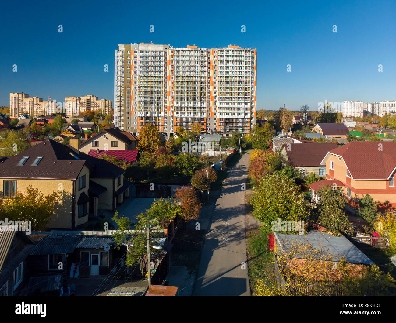 High-rise residential building under construction among private houses in Russia Stock Photo