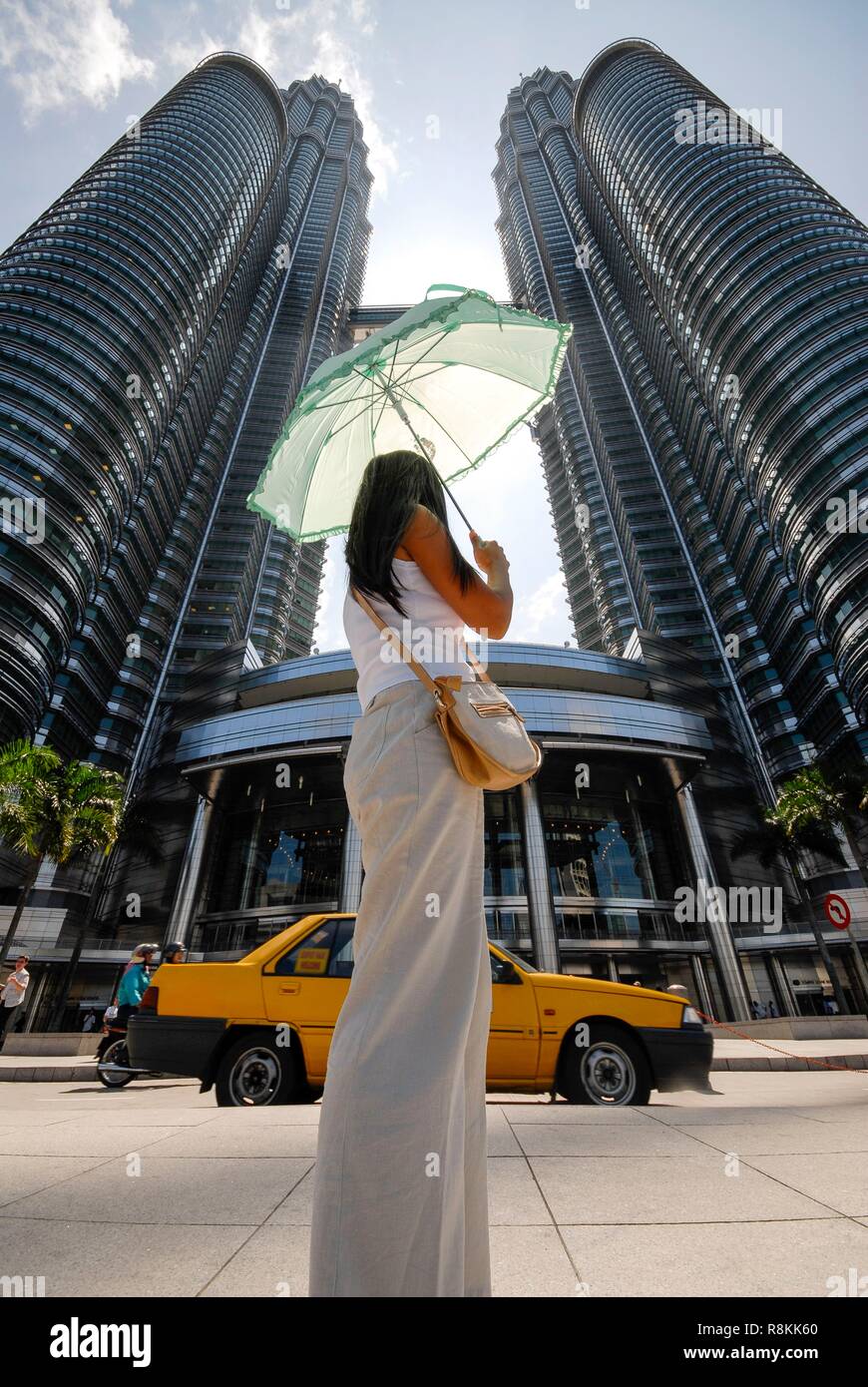 Malaysia, Kuala Lumpur, downtown, the Petronas Twin Towers by architect Cesar Pelli, 452m high with 88 floors opened in 1998, a woman standing in front of the building Stock Photo