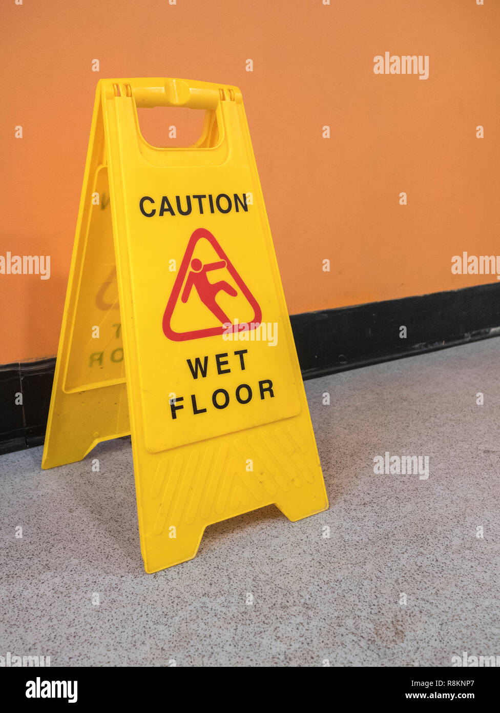 Yellow hazard sign warning 'Caution Wet Floor'. Metaphor slippery, falling, slip, financial risk, slippery slope. Slippery surface pictogram. Stock Photo