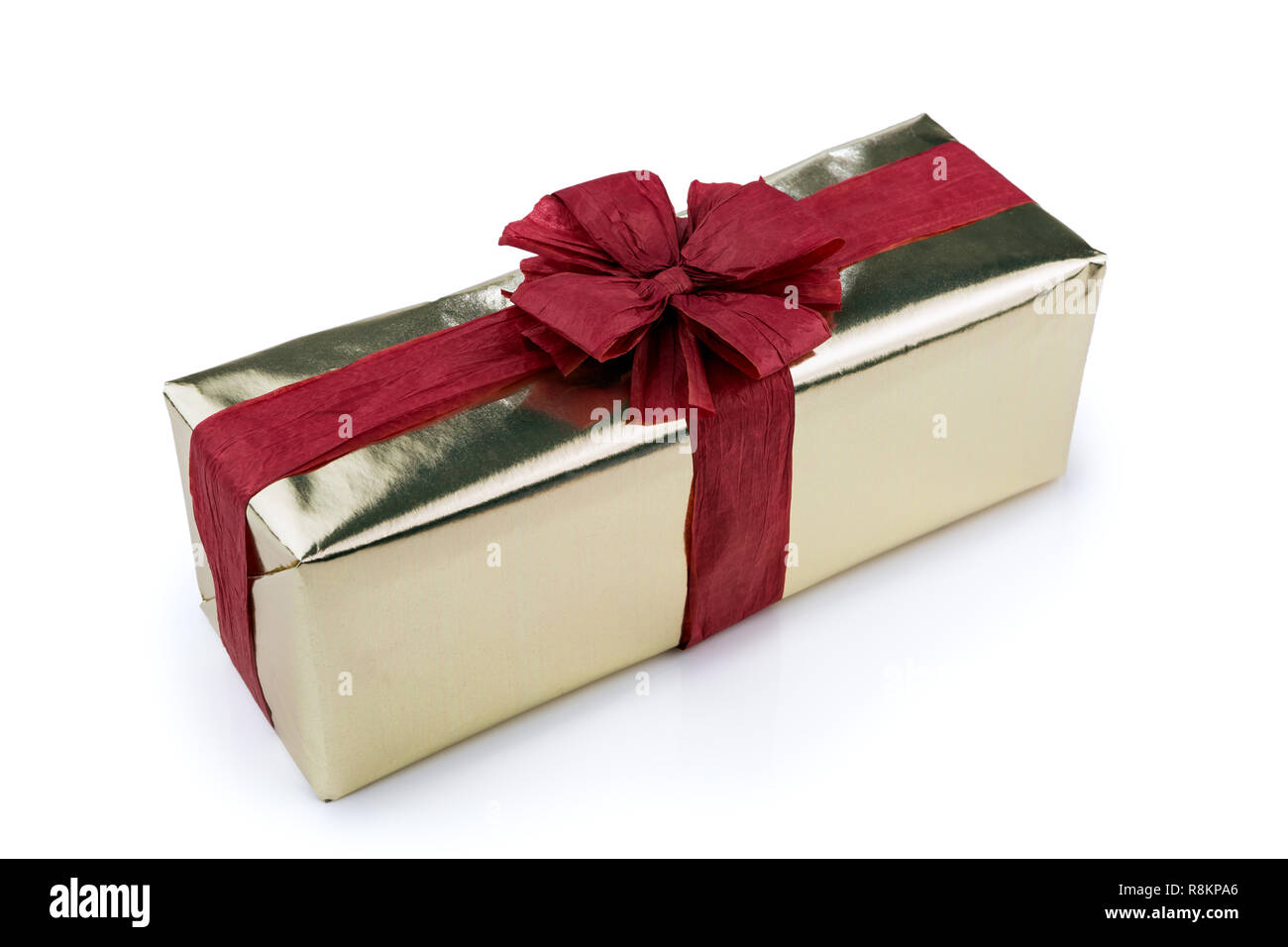 Gift box wrapped in gold wrapping paper, decorated with red raffia