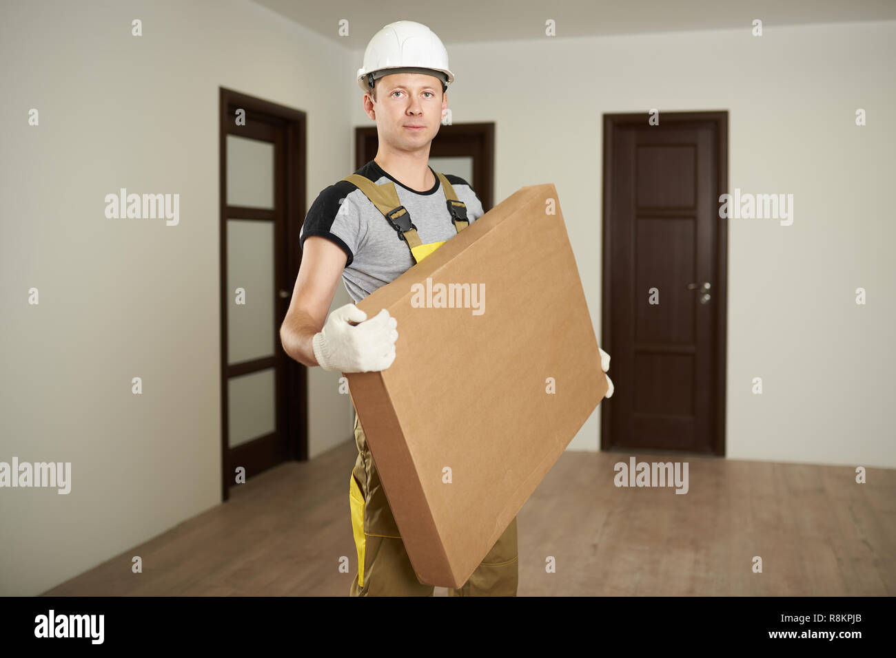 Man carry box. Worker hold package furniture box in house background Stock Photo