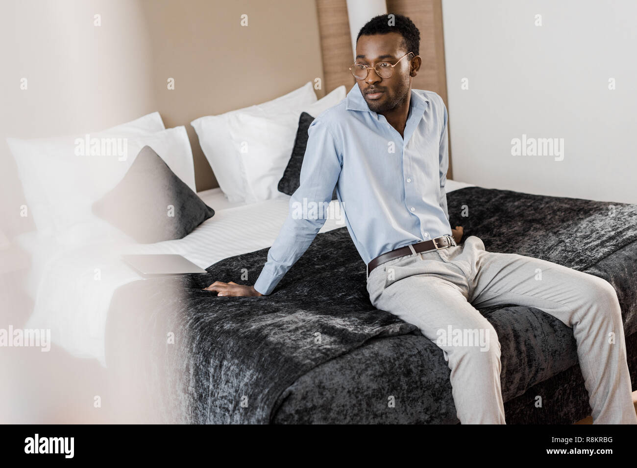 handsome african american man sitting on bed in hotel room Stock Photo -  Alamy