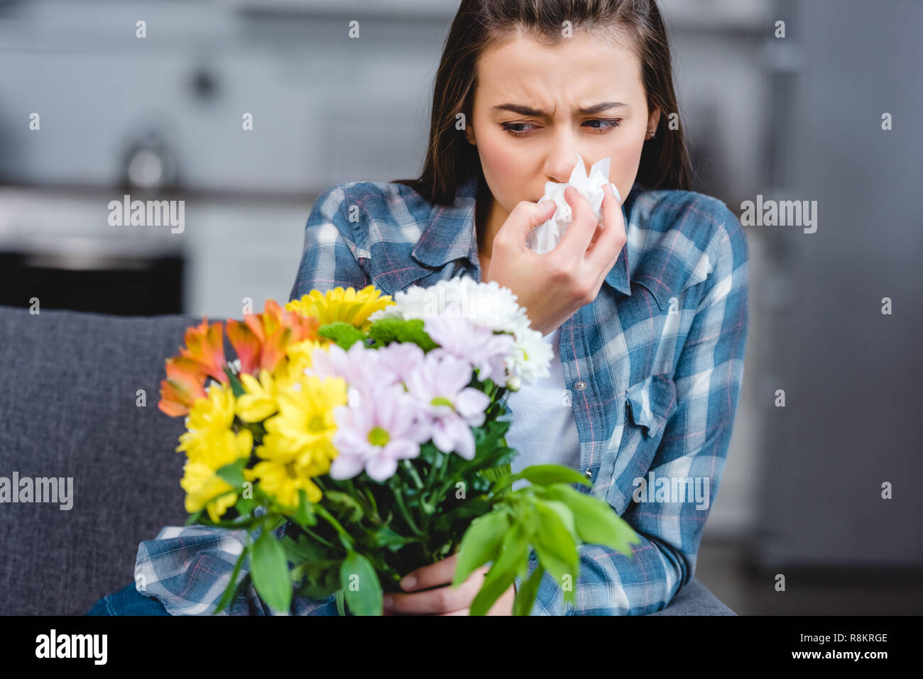 girl with allergy holding facial tissue and looking at flowers Stock