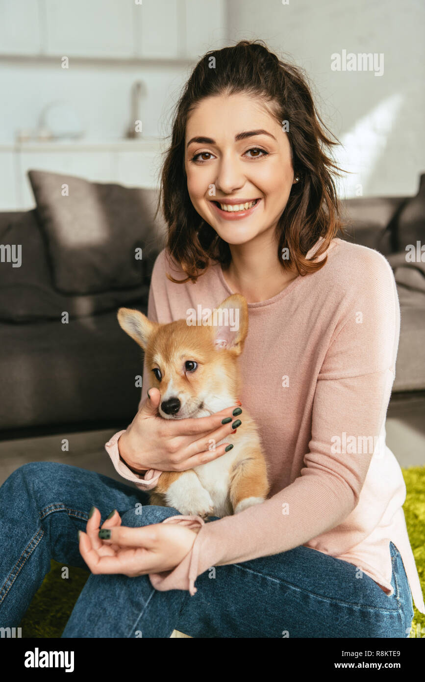 laughing woman with cute welsh corgi pembroke at home Stock Photo