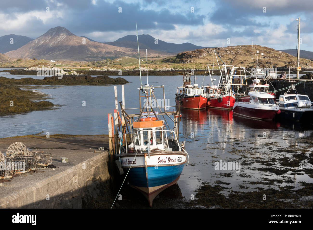 Ireland, County Galway, Ballynakill, Connemara, wooden boats and fishing boats in the harbor, Tully Mountains and Twelve Bens mountains in the background Stock Photo