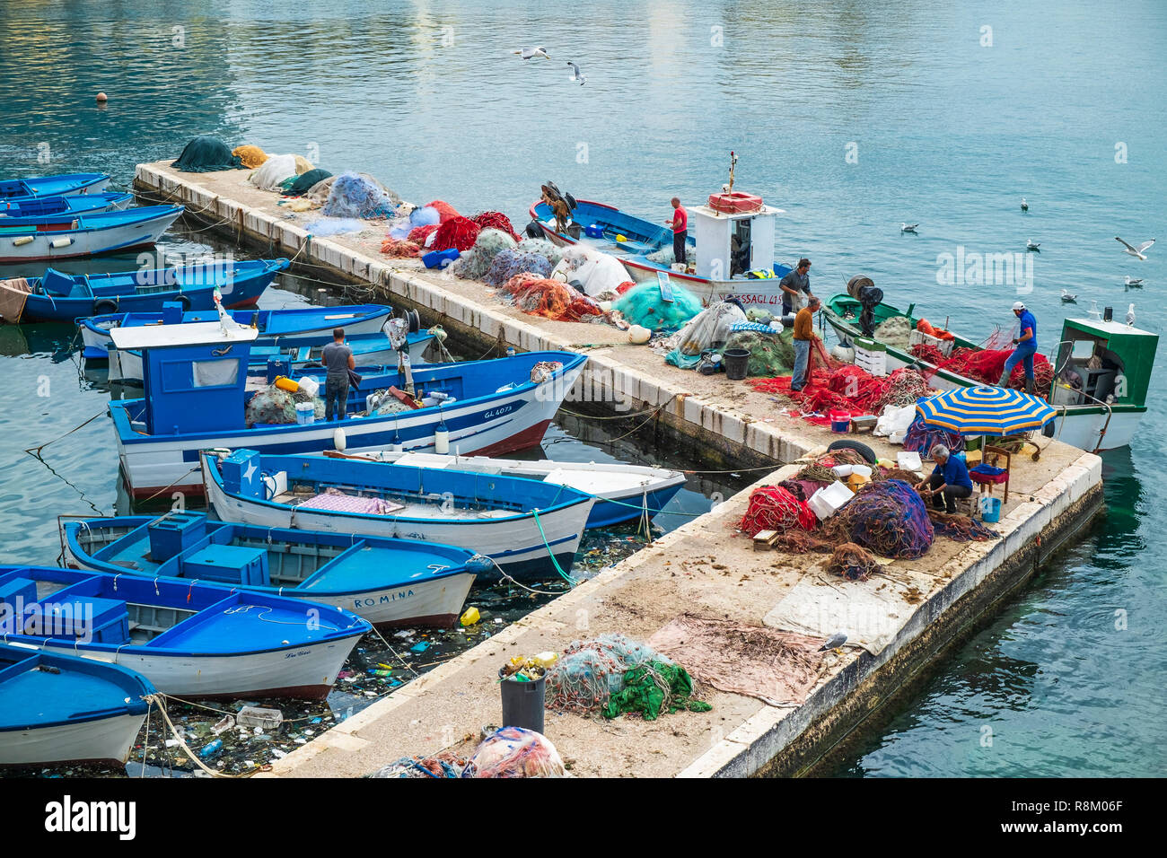 Italy, Apulia, Salento region, Gallipoli, fishermen preparing their fishing nets in the fishing harbour Stock Photo