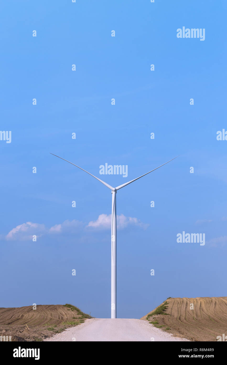 One single windmill turbine in front of road with blue sky in ...