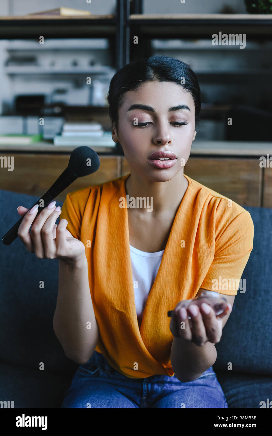 Beautiful Mixed Race Girl In Orange Shirt Applying Face Powder At