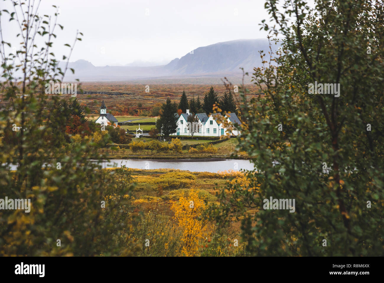 Village with farms in a rural area of the mountains of Iceland, with snowy mountains in the background. Stock Photo