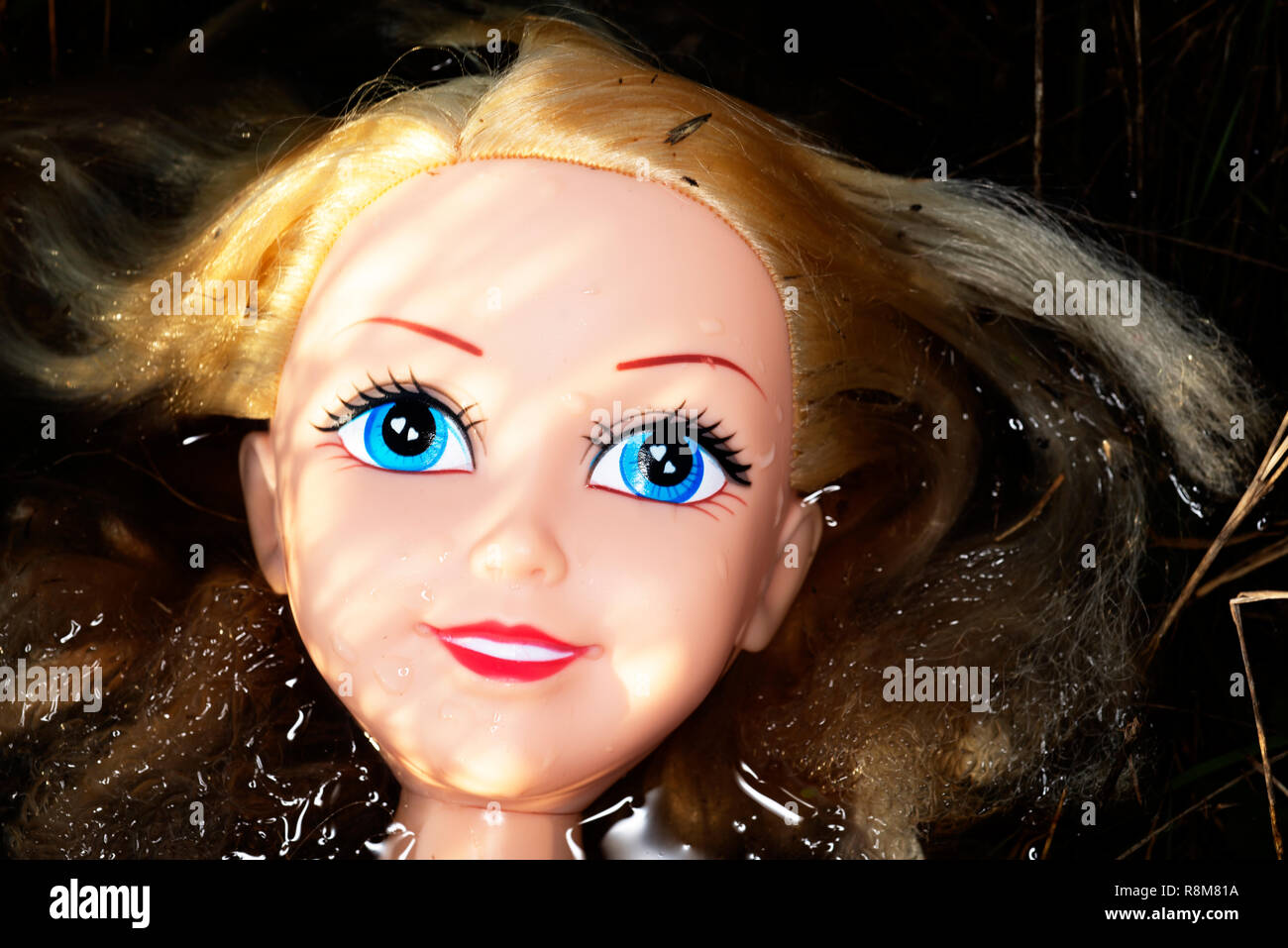 Toy doll discarded in a ditch Stock Photo - Alamy