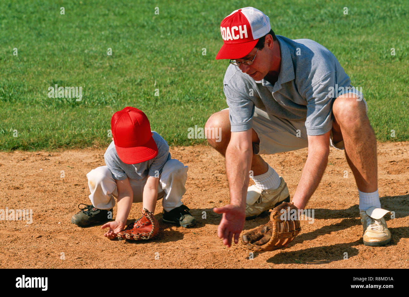 Coach Teaching Son to catch a ground ball in Baseball, USA Stock Photo