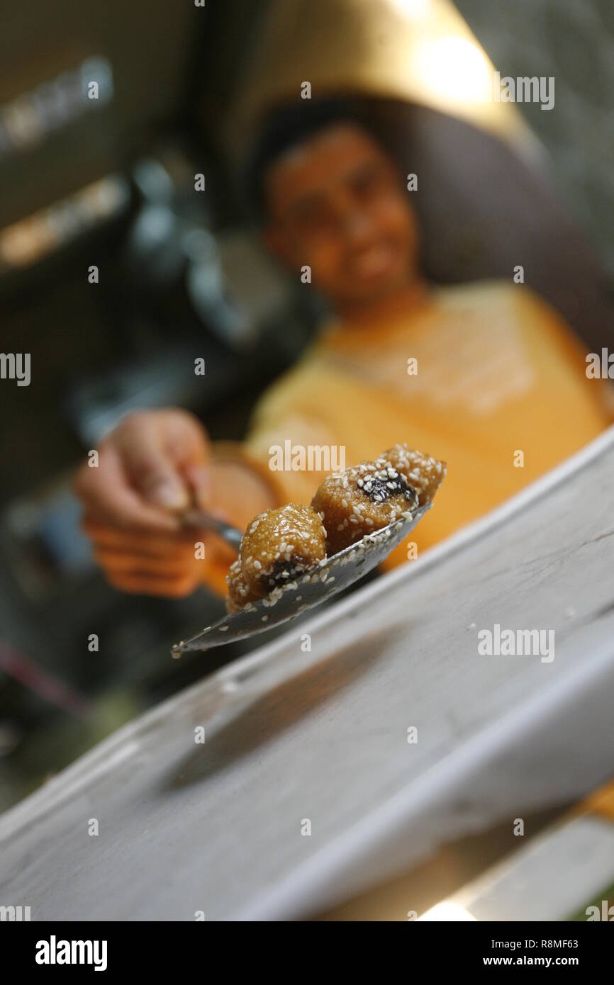 Local pastry chef in Tunis offers a piece of the sweets his sells, as a gesture of welcome in the town. Stock Photo